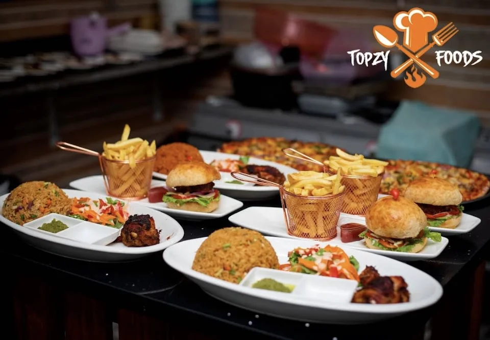 A table of Topzy Foods pizza, rice, chicken and burgers