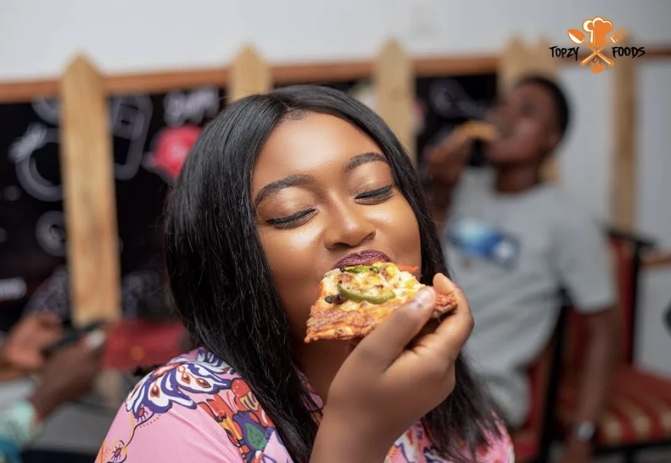 A diner enjoying pizza at Topzy Foods